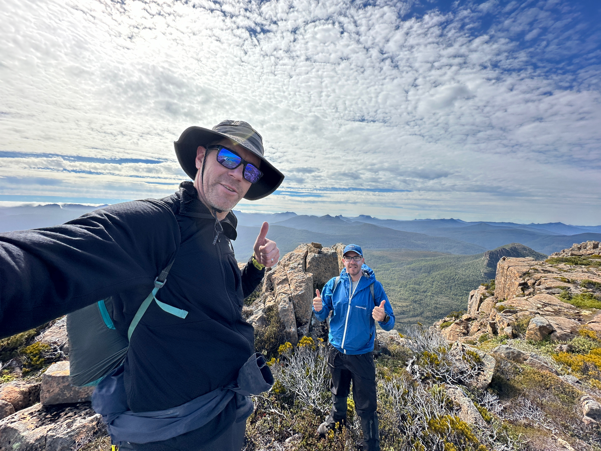 Hikers on Tasmanian mountain summit with dramatic landscape views