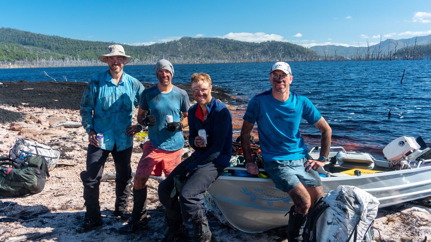 Mowser and three mates on a rocky shore beside a boat